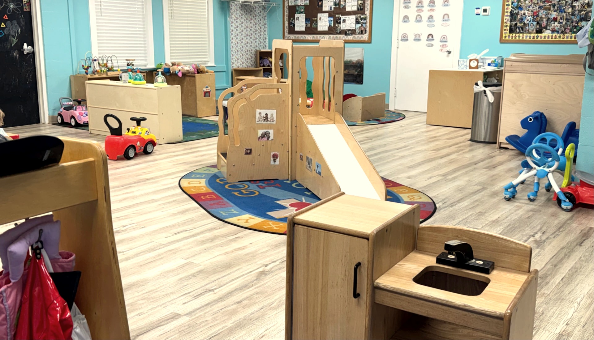 Bright toddler classroom with wooden play structure and learning toys